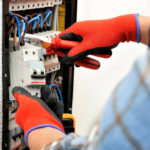 Young electrician technician at work on a electrical panel with protective gloves